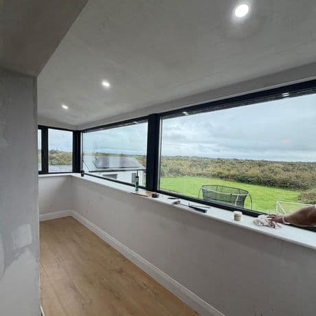 Interior view of long fixed picture windows with black frames and garden views
