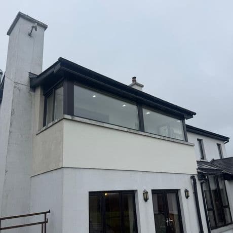 Large fixed picture windows with black frames above a rendered extension wall